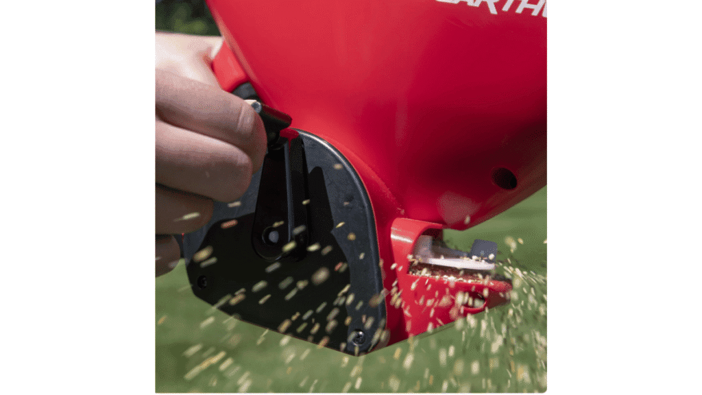 A homeowner using a hand-held spreader to apply bait granules for Harvester ant control.