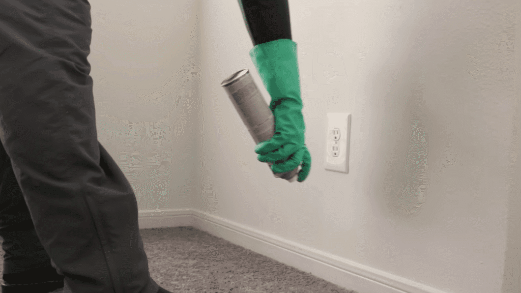 Homeowner using an aerosol spray along the baseboard and near an outlet to treat for German cockroaches.