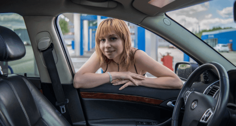 Person leaning into a vehicle at a gas station, viewed from inside the car interior, for the guide on how to get rid of ants in your car, truck, or SUV
