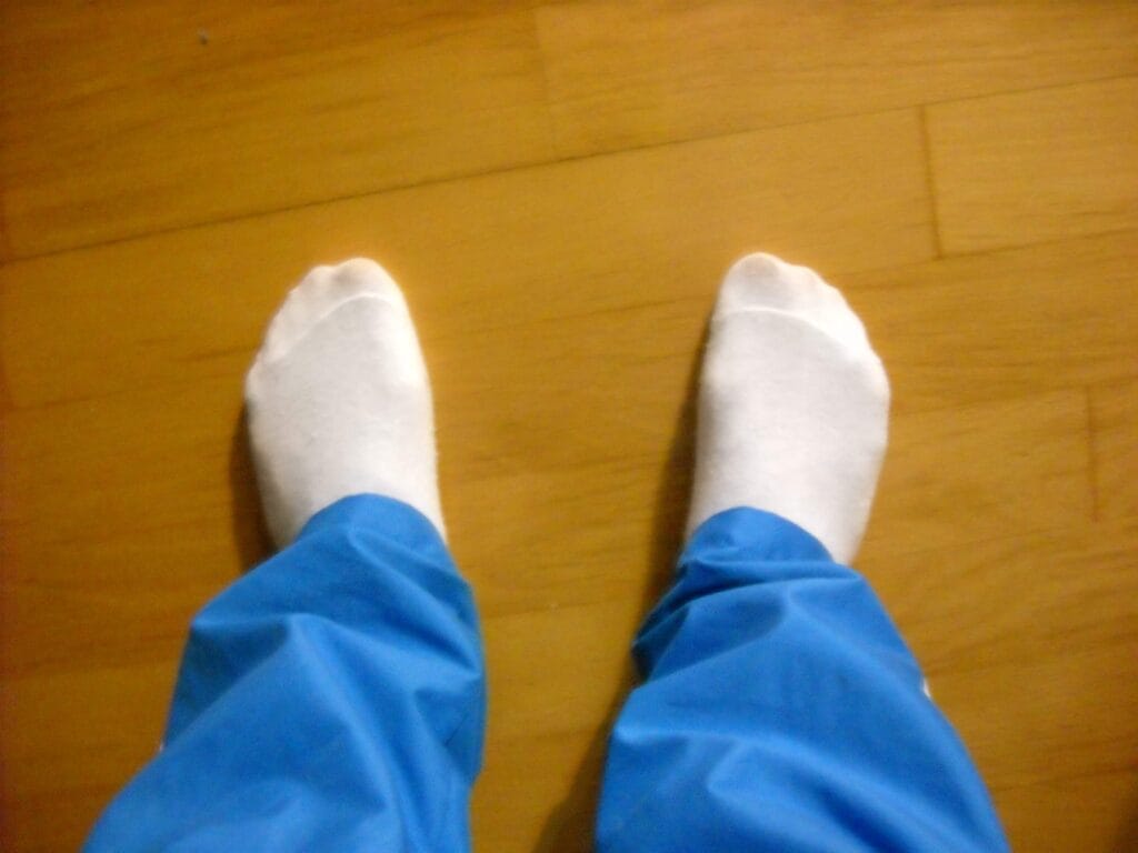 A person wearing white socks and long pants performing a flea test on car carpet.